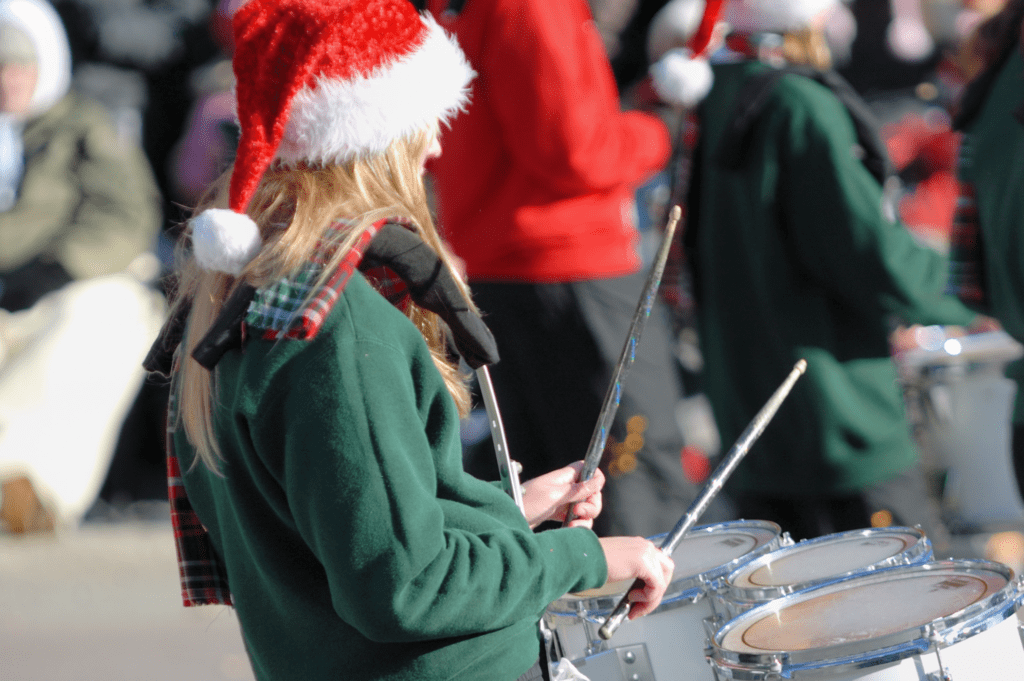 A girl playing drums with a Santa hat on